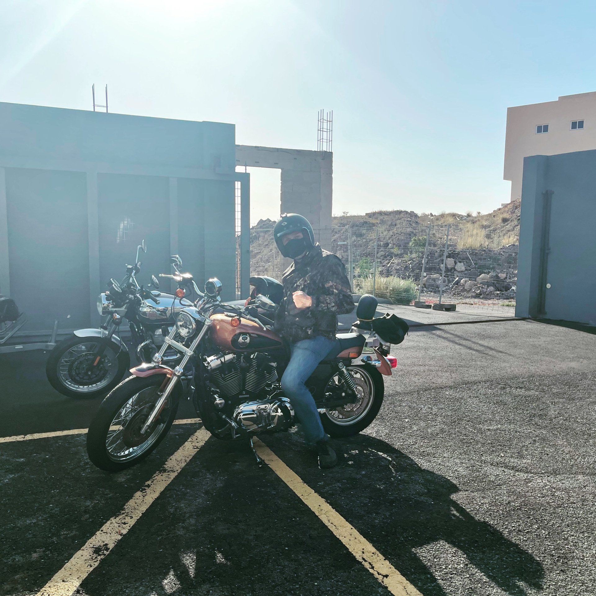 A man is sitting on a motorcycle in a parking lot