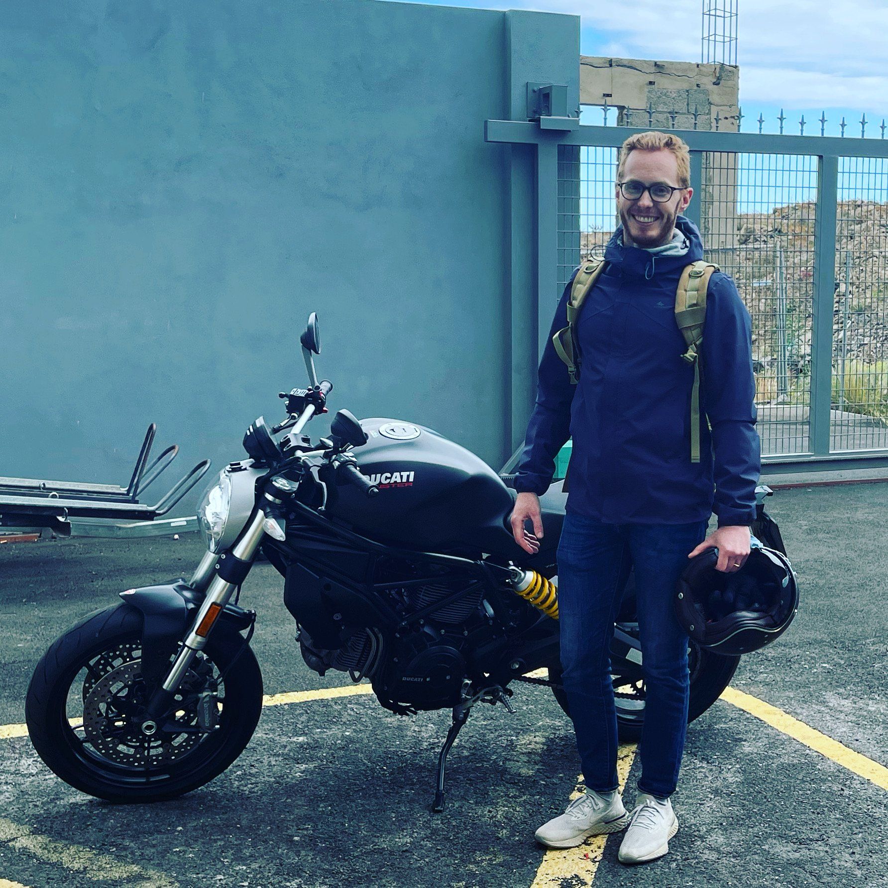 A man standing next to a black ducati motorcycle