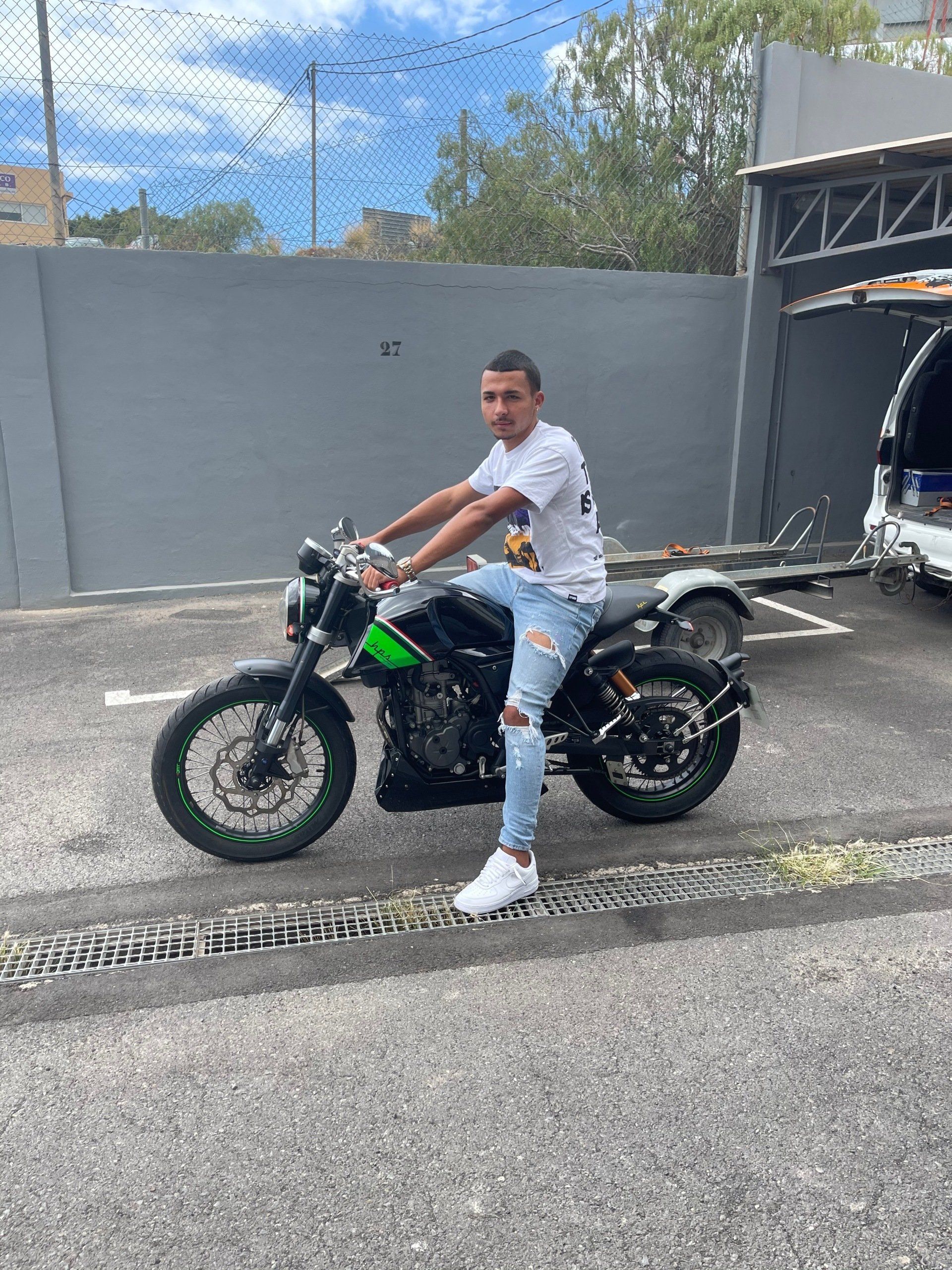 A man is sitting on a motorcycle in a parking lot.
