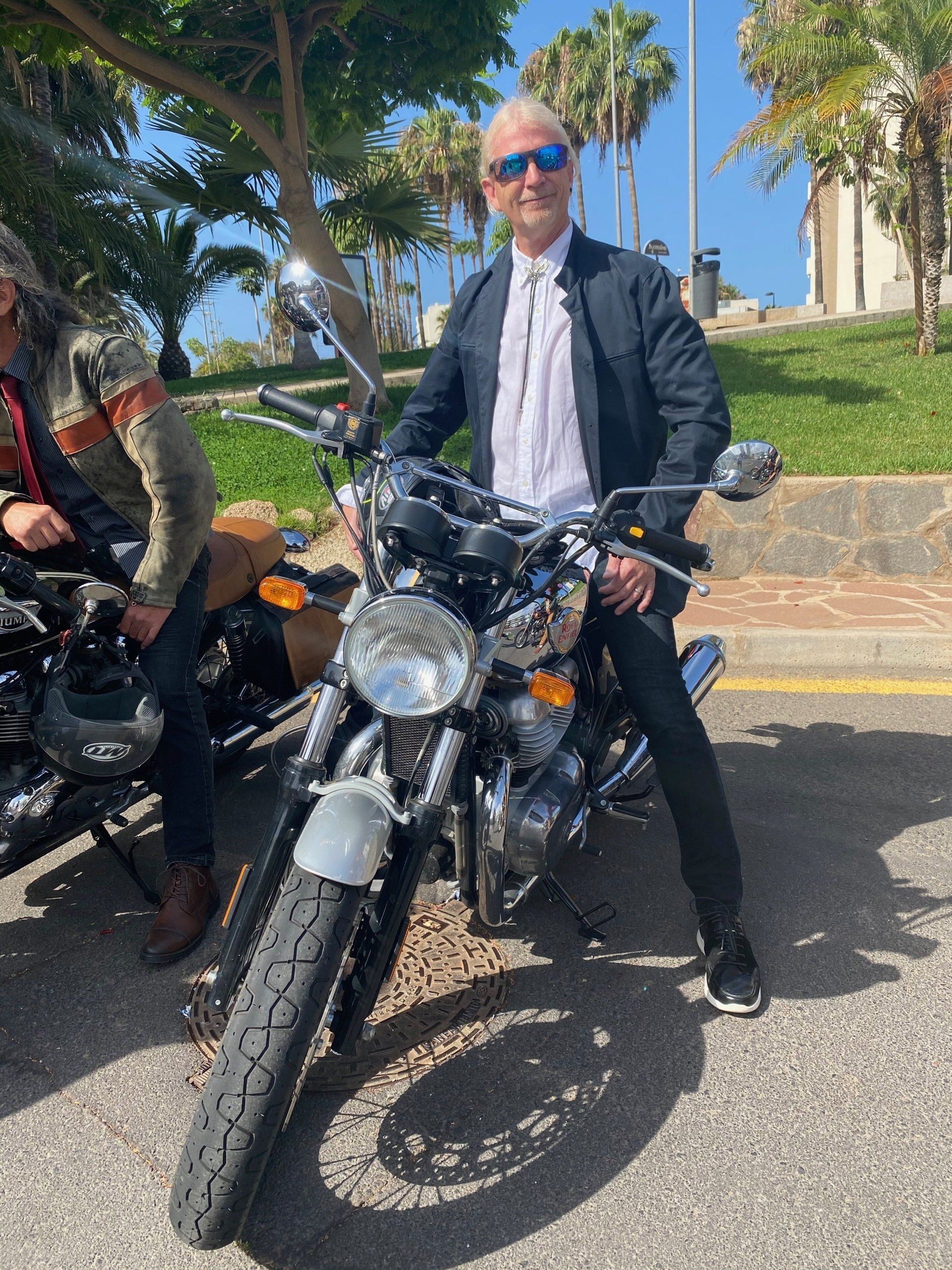 A man in a suit and tie is standing next to a motorcycle.