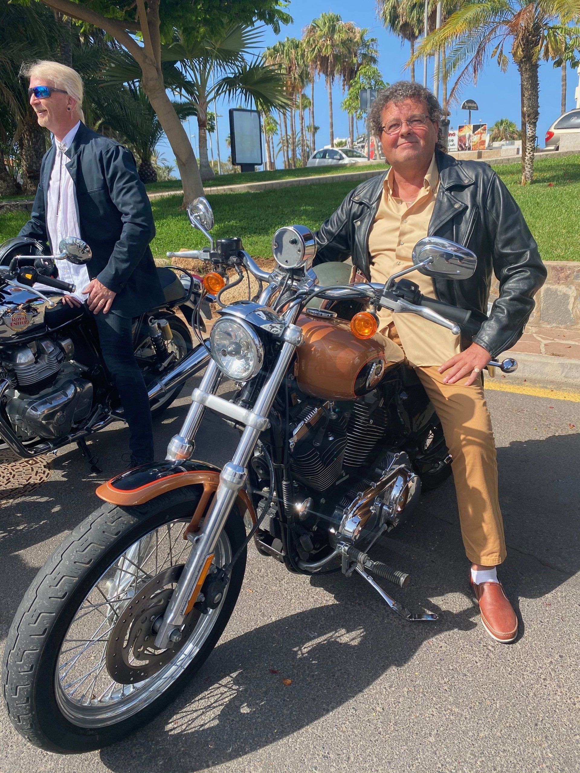 A man in a leather jacket is sitting on a motorcycle.