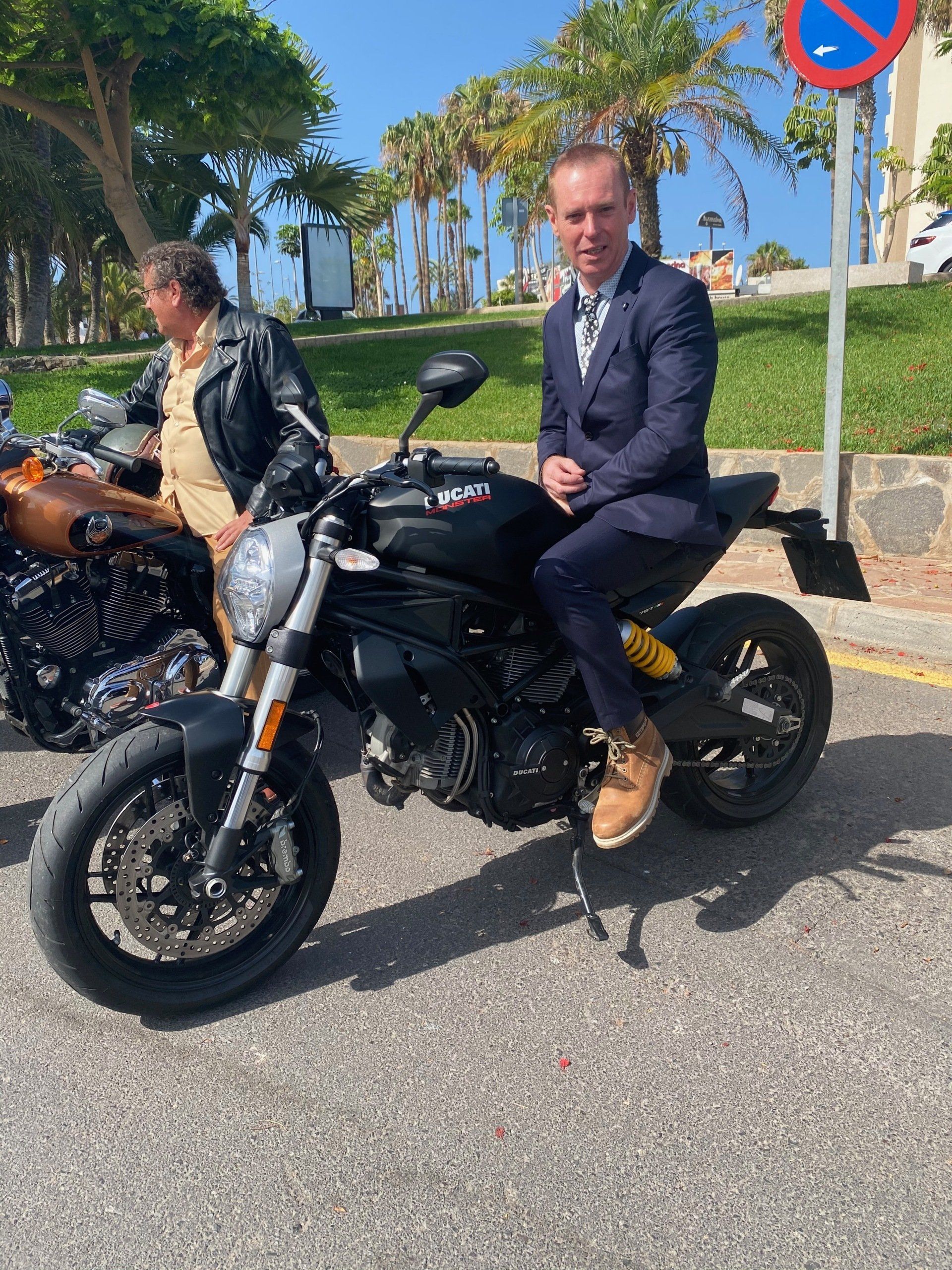 A man in a suit is sitting on a motorcycle.