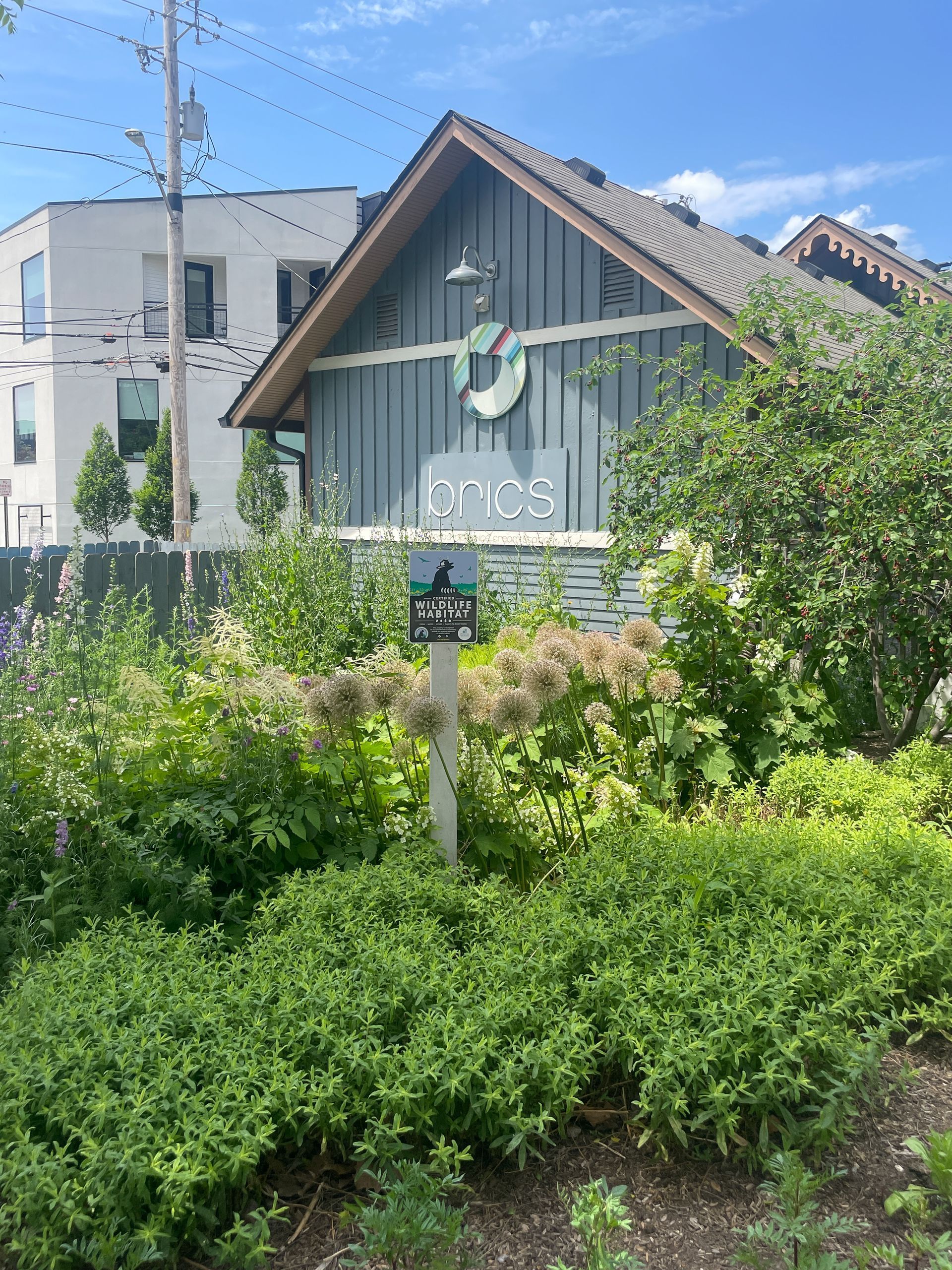 A house with a sign in front of it and a lot of plants.