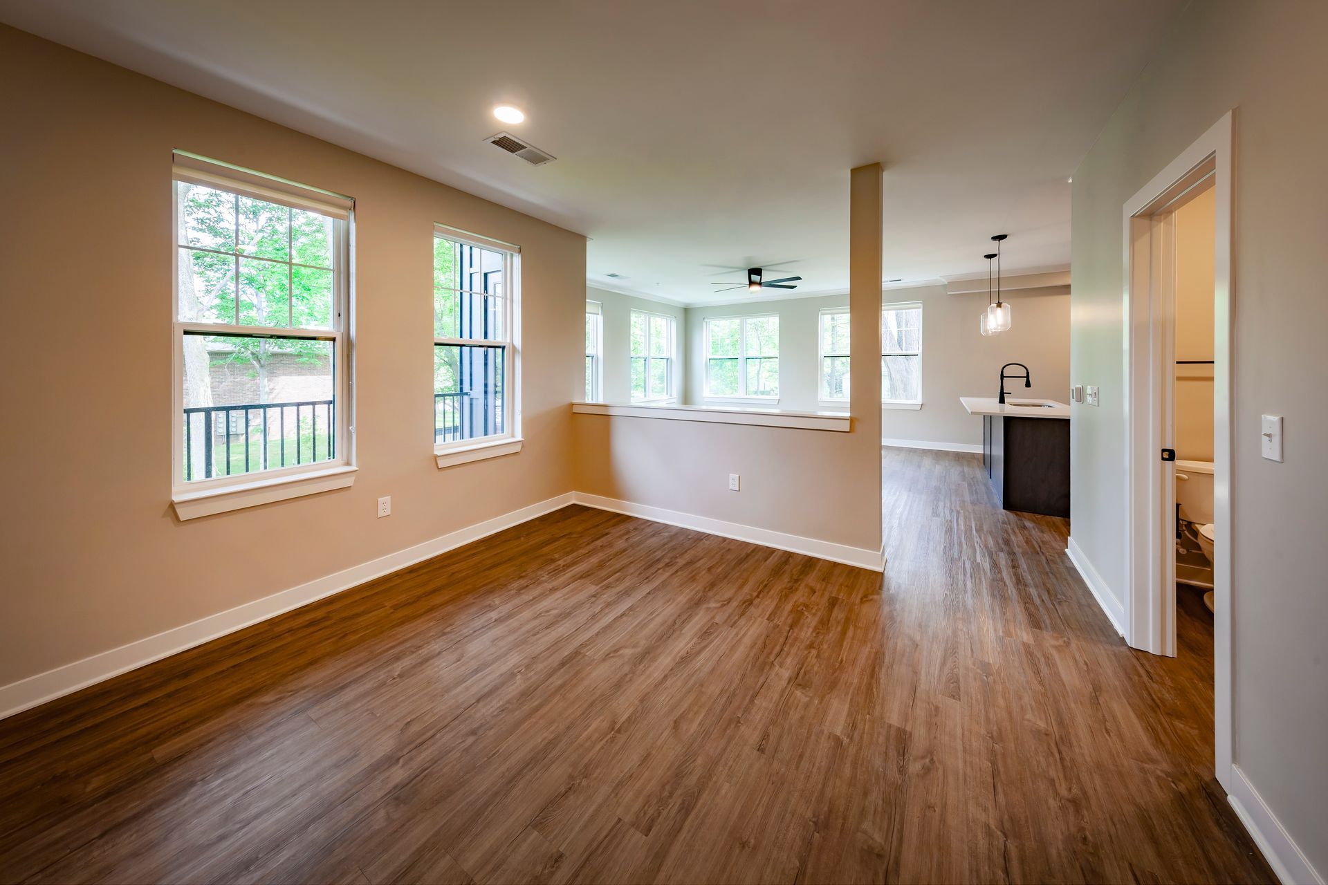 An empty living room with hardwood floors and lots of windows.