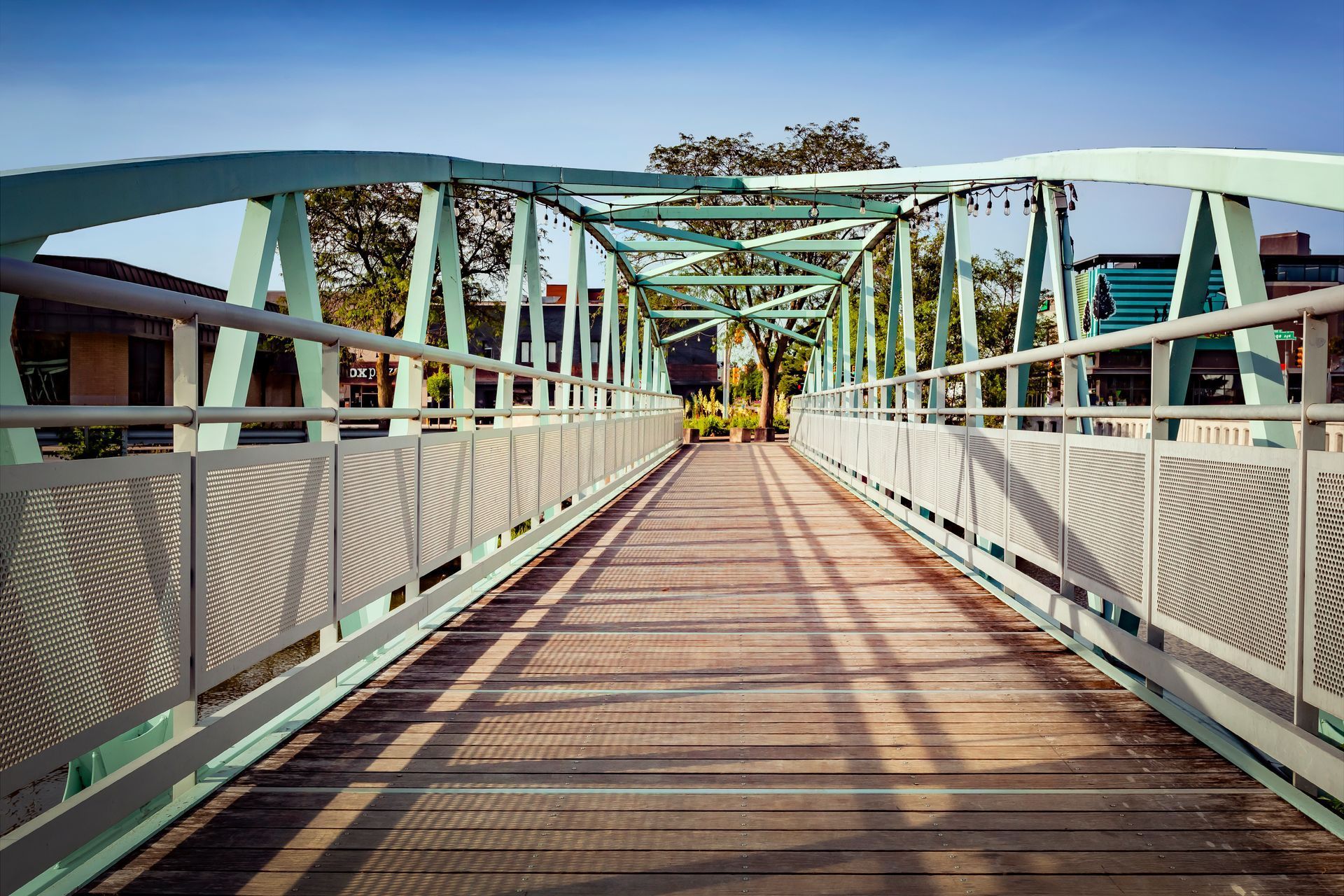 A wooden bridge with a metal railing and a blue sky in the background.