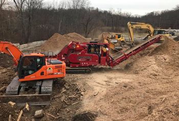 A bulldozer and a conveyor belt are sitting on top of a pile of dirt.