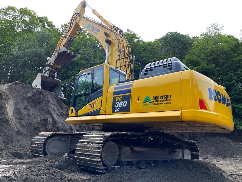 A yellow excavator is sitting on top of a pile of dirt.