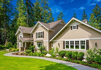 A large house with a lush green lawn and trees in the background.