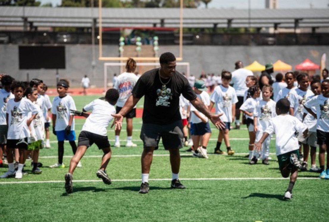 A man is playing soccer with a group of children on a field.