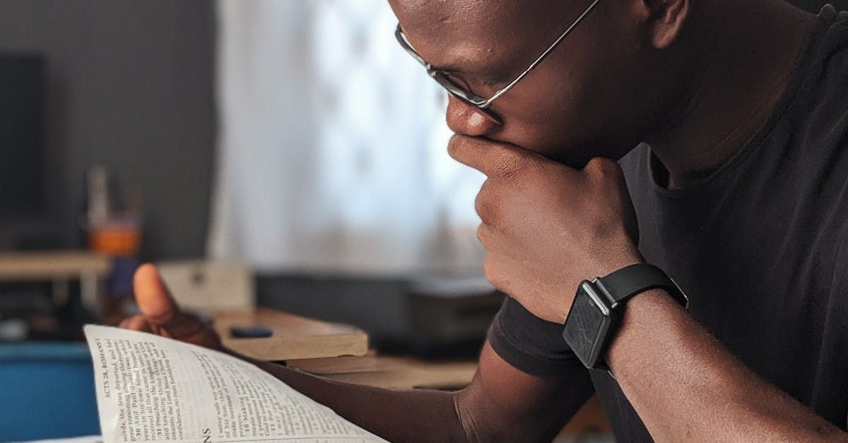 A man wearing glasses is reading a book.