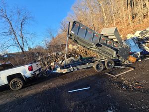 A white truck is towing a dumpster on a trailer.