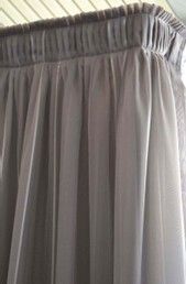 Grey sheer curtain with pleated top detail hanging from a ceiling-mounted track