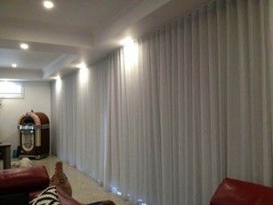 A long wall of floor-to-ceiling windows covered with white sheer curtains in a modern living room