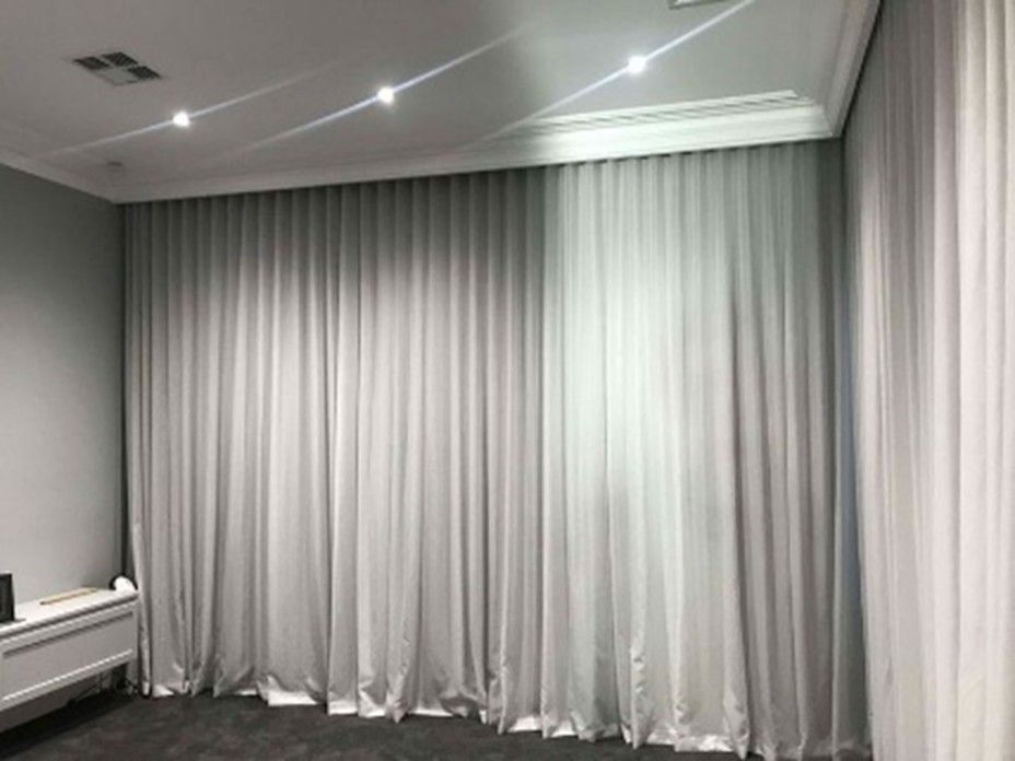 An empty room with grey floor-to-ceiling curtains, white ceiling lights, and light grey walls