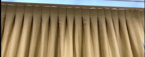 Beige pleated curtains hanging from a ceiling-mounted track in a modern interior room