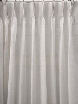 White pleated curtains hanging from hooks on a curtain rod in a modern interior room