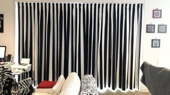 A living room with black and white vertical striped curtains behind a white sofa and small desk