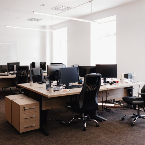 An office with a lot of desks and chairs with computers on them