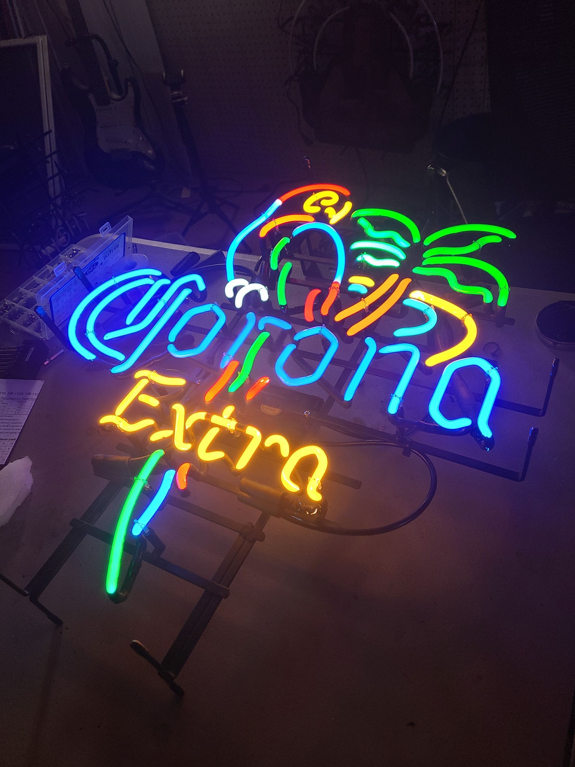 Neon Corona Extra sign with parrot and palm tree in blue, yellow, and green.