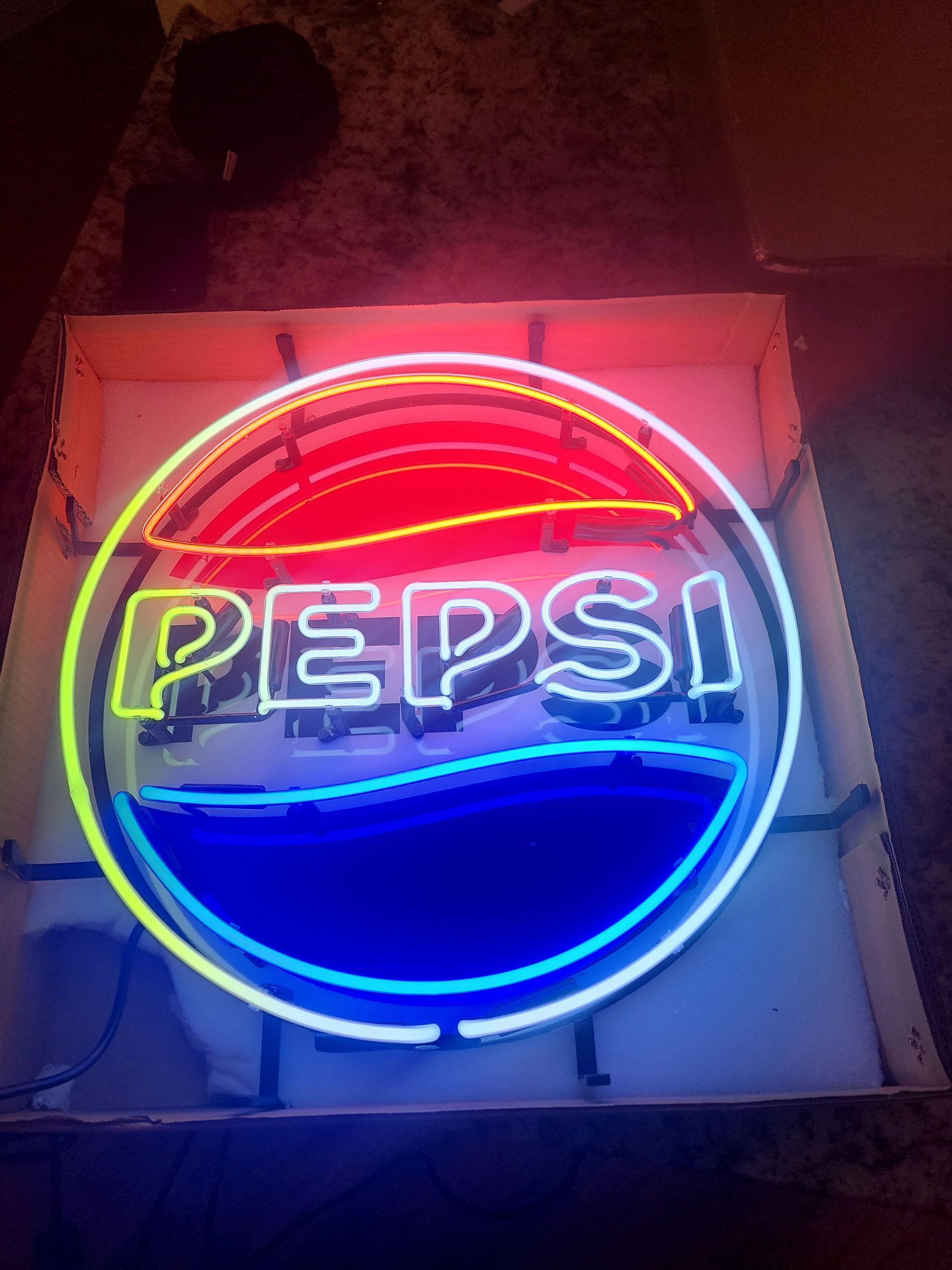 Neon Pepsi sign, red, blue, and white colors, in a circular frame.