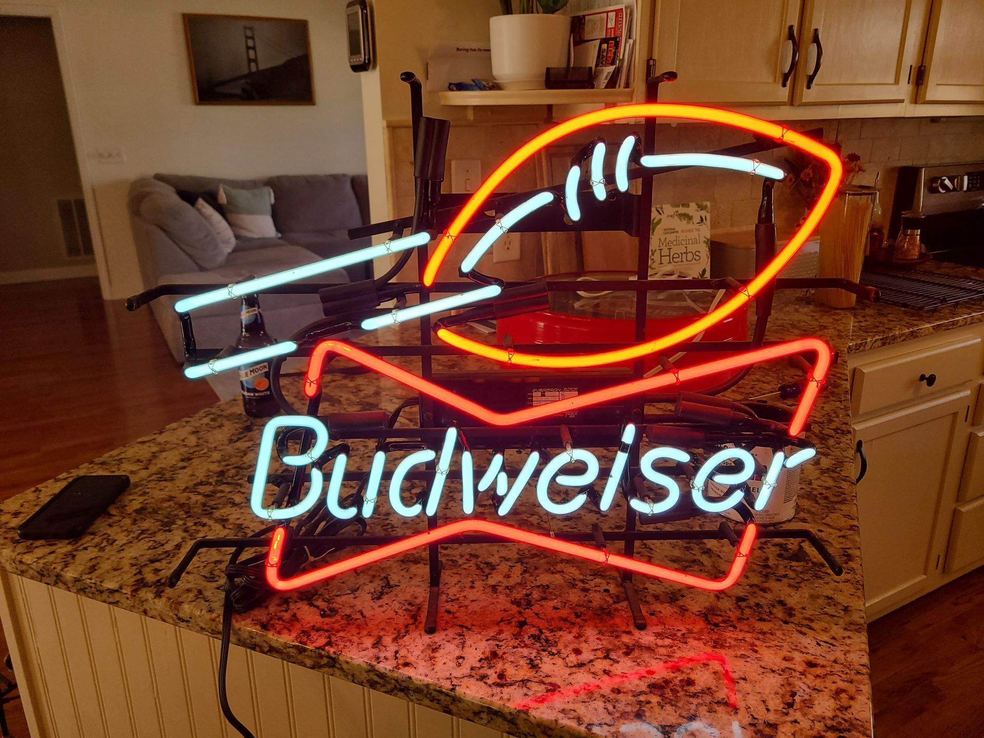 Budweiser neon sign with football on a kitchen counter.