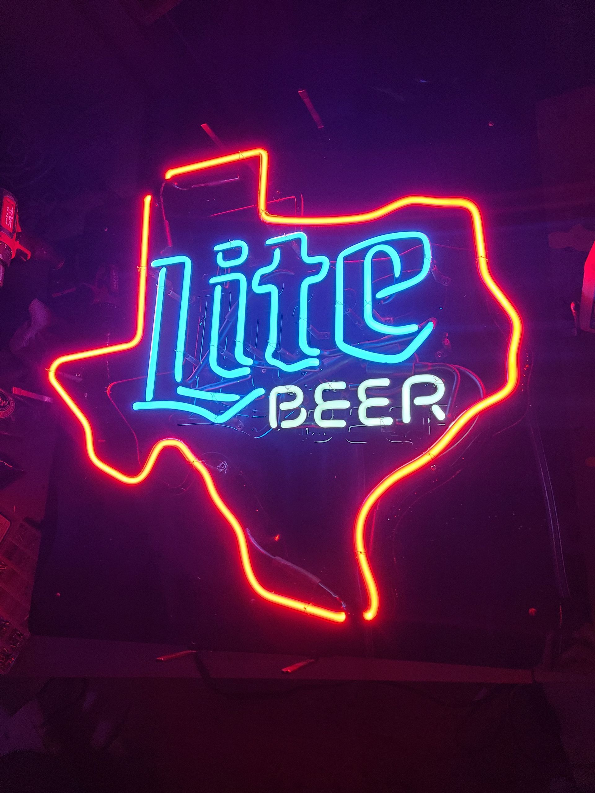 Neon sign in the shape of Texas, red outline, blue 
