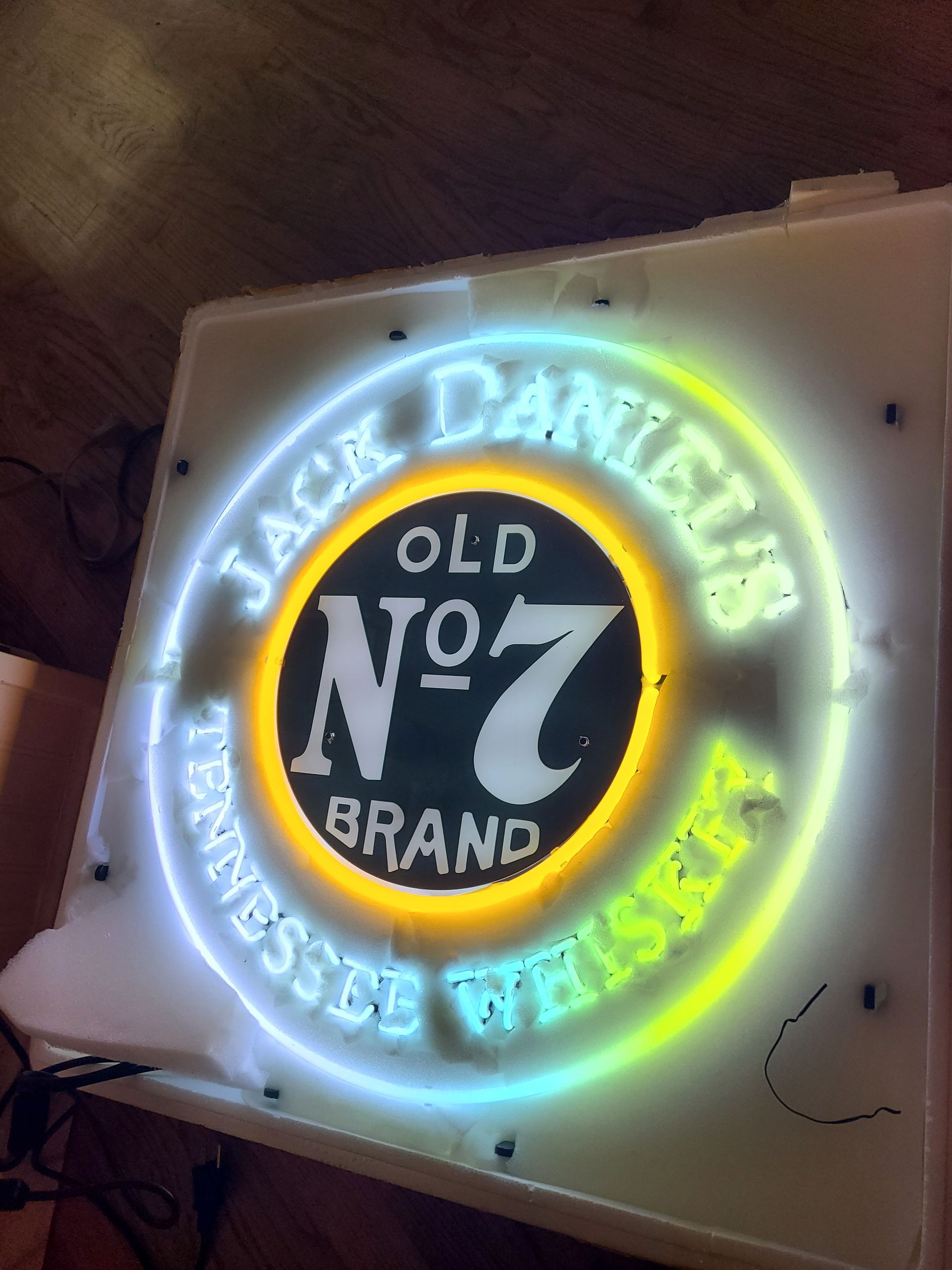 Jack Daniel's neon sign. White letters on blue circle, yellow center with black 