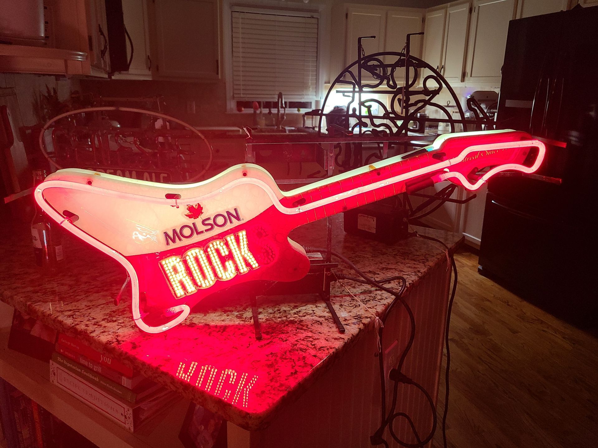 Neon Molson Rock guitar sign, red and white, on a countertop.