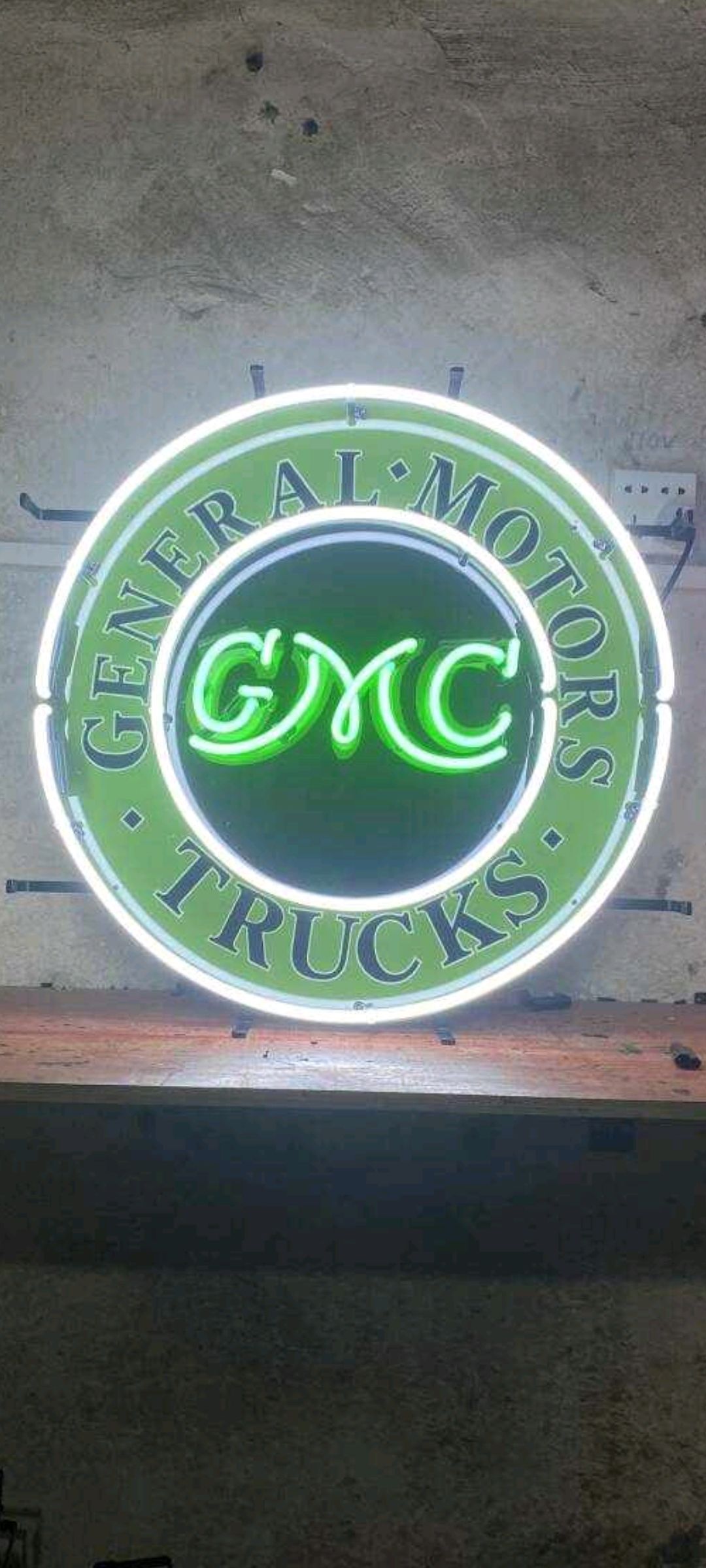 Neon GMC Trucks sign with a green and white glow.