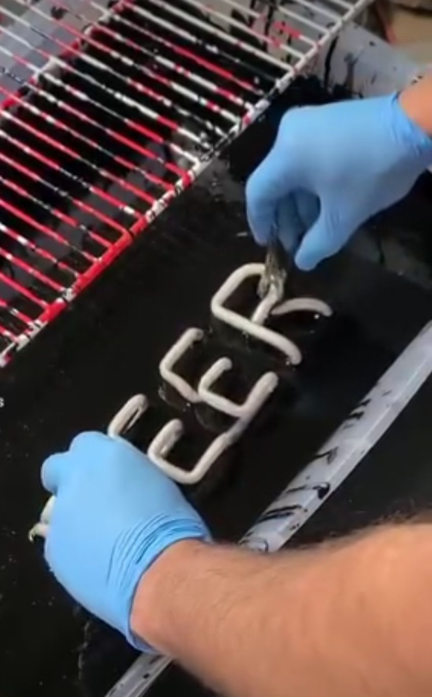 Blue neon tube in a wavy line shape, with yellow wires connected on a dark surface.