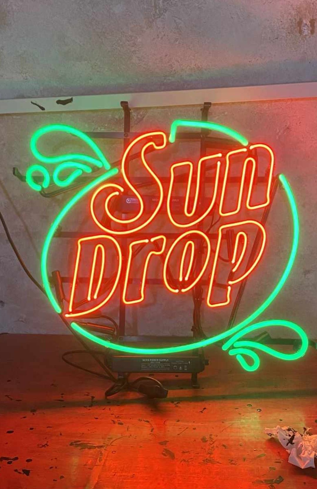 Neon Sun Drop sign, red letters, green border and accents.