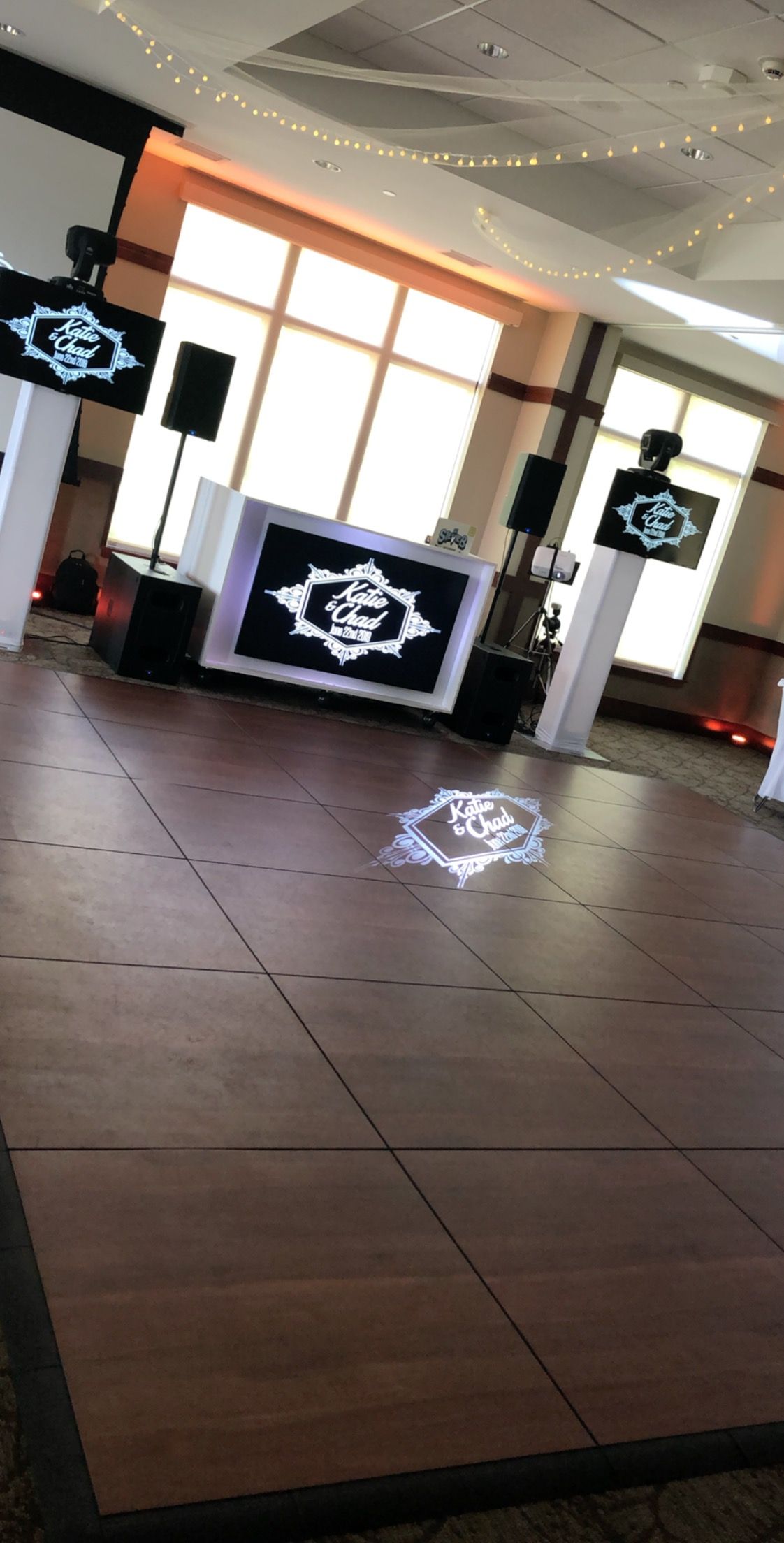 DJ setup with lighted logo on dance floor and display screens.