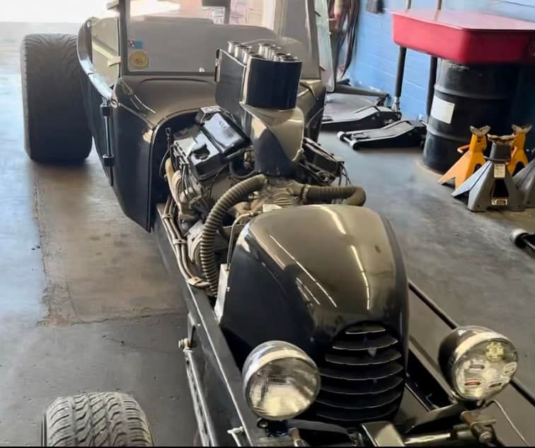 A black lawn mower is parked in a garage