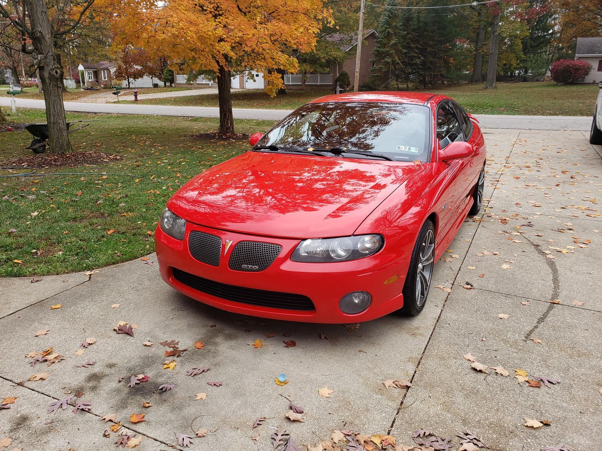 A red pontiac gto is parked in a driveway.