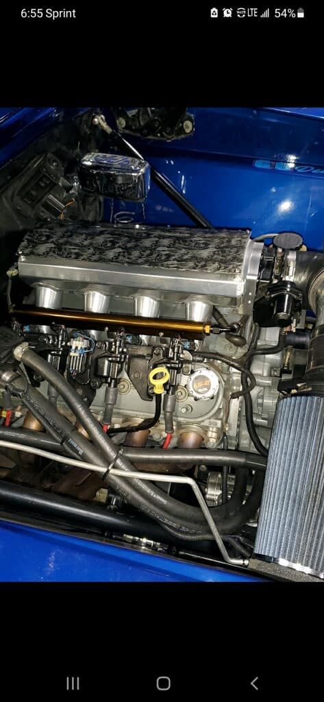 A close up of a blue car engine with a hood open.