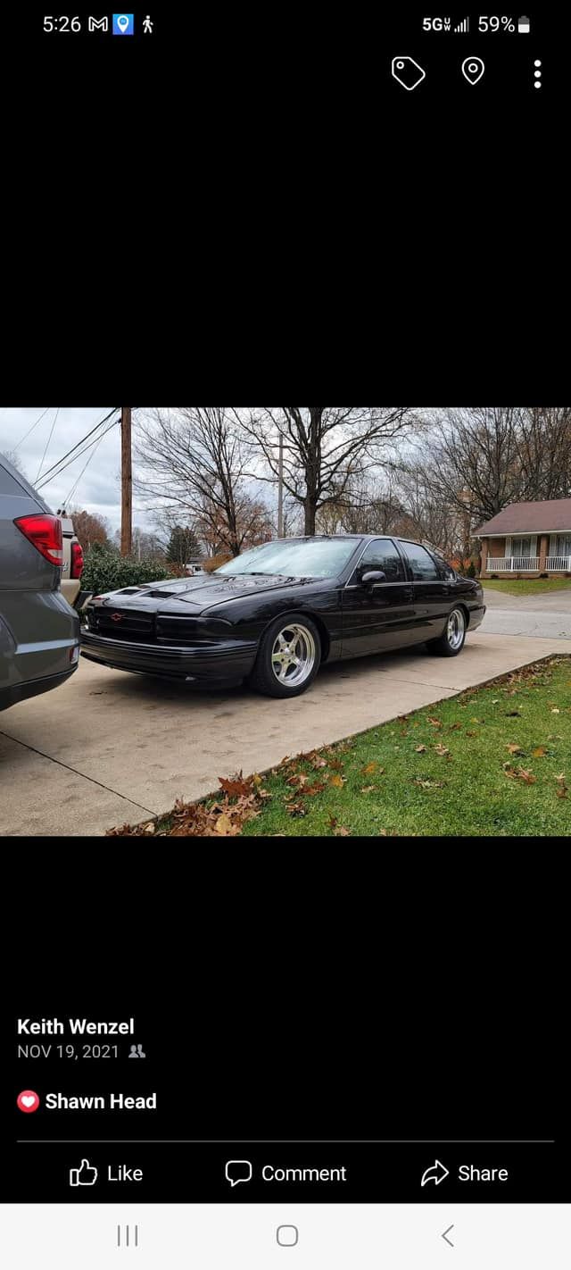 A black car is parked on the side of the road next to a van.