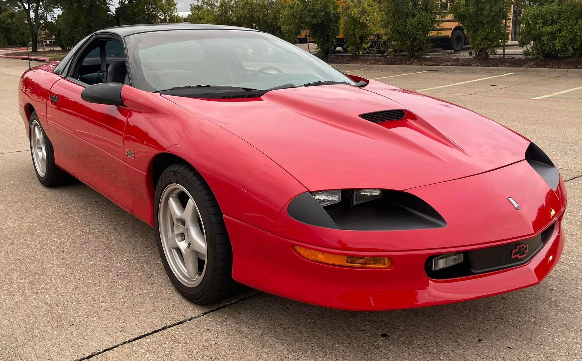 A red chevrolet camaro is parked in a parking lot.