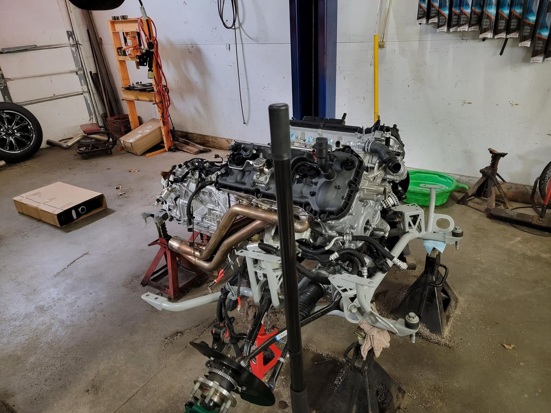 A car engine is sitting on a lift in a garage.