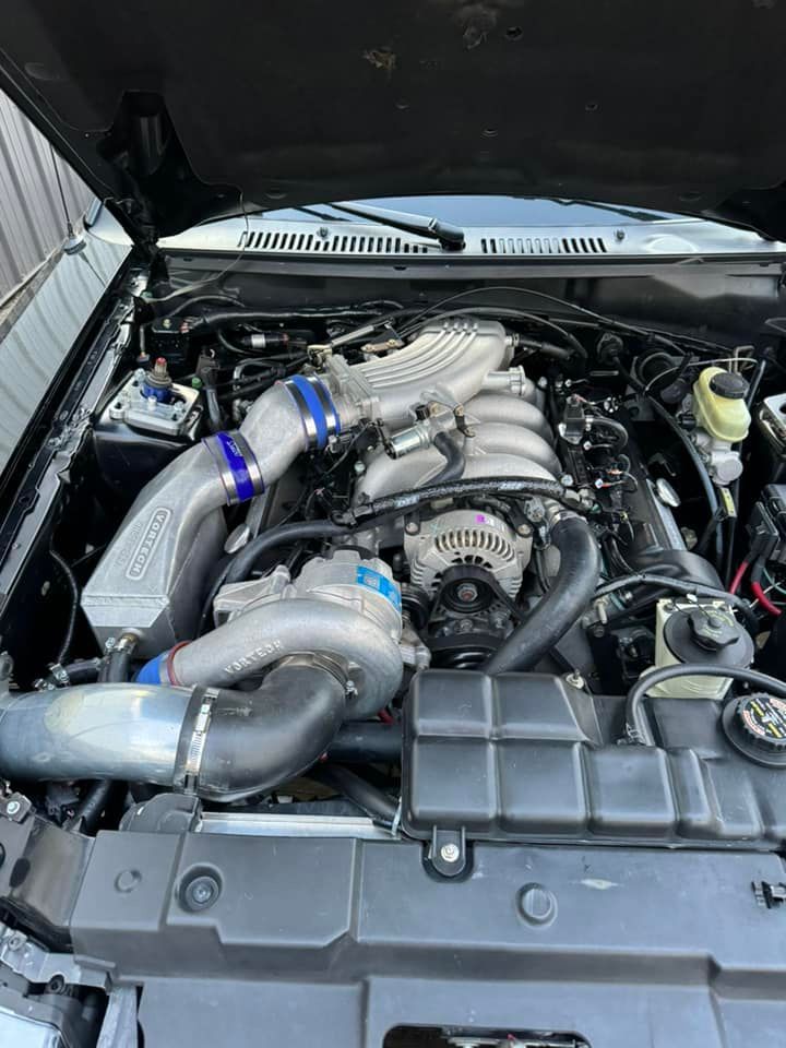A close up of a car engine with the hood up.