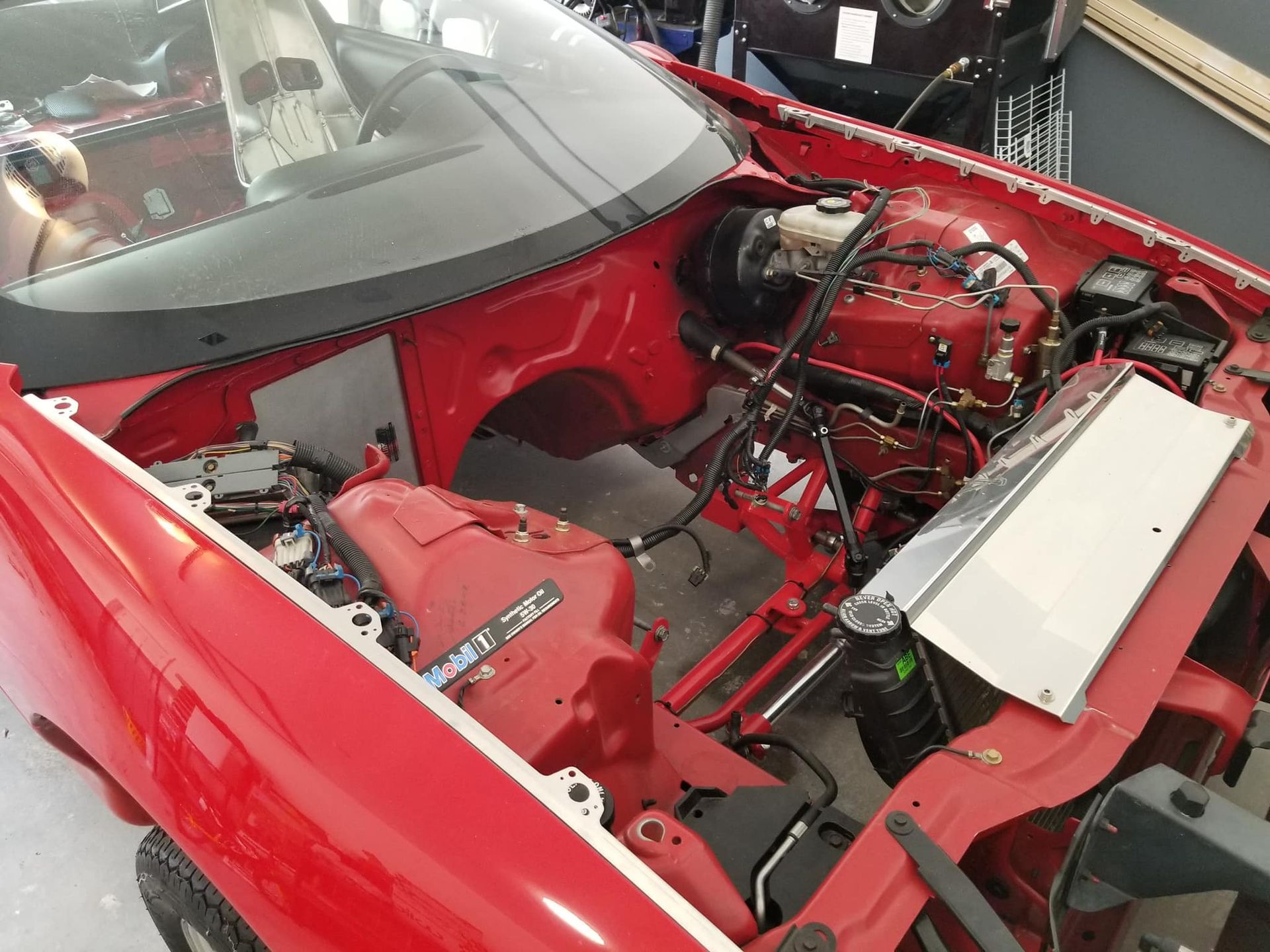 A red car with the hood open and the engine visible