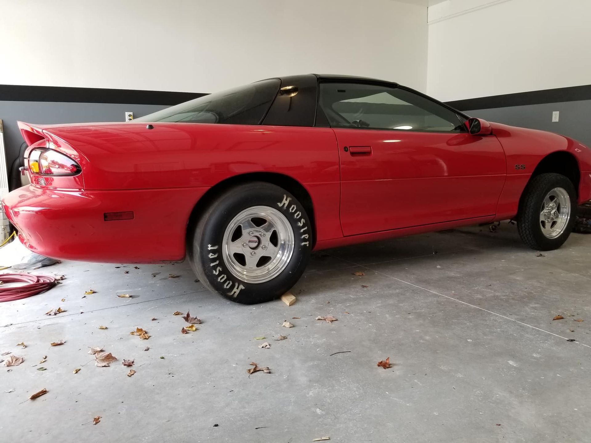 A red chevrolet camaro is parked in a garage.