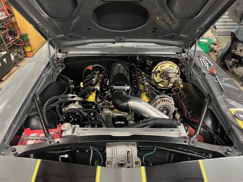 A close up of a car engine with the hood open