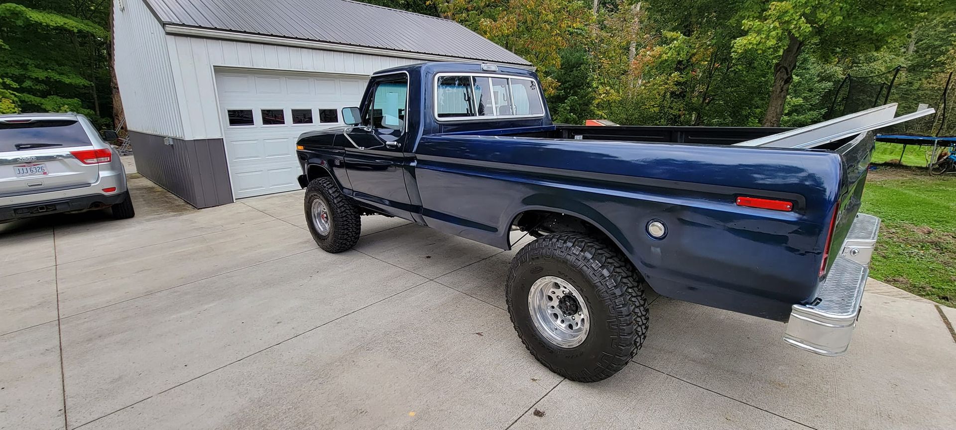 A blue truck is parked in a driveway next to a garage.