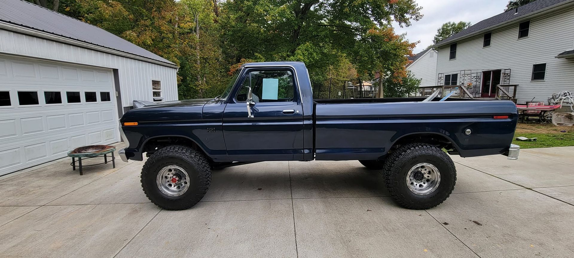 A blue pickup truck is parked in a driveway in front of a garage.
