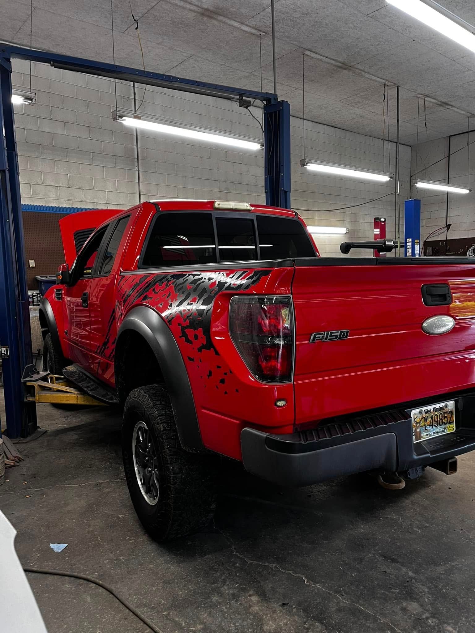 A red truck is sitting on a lift in a garage.