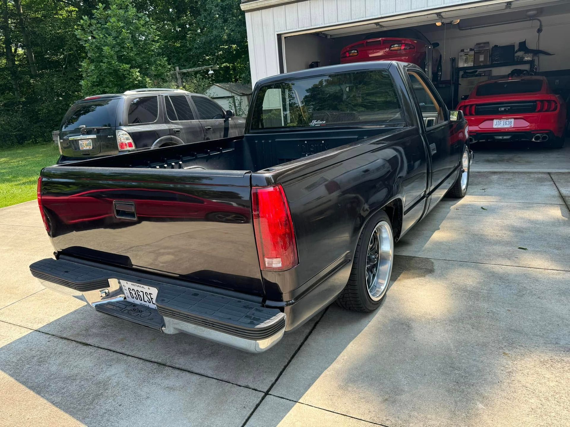 A black truck is parked in a driveway next to a garage.