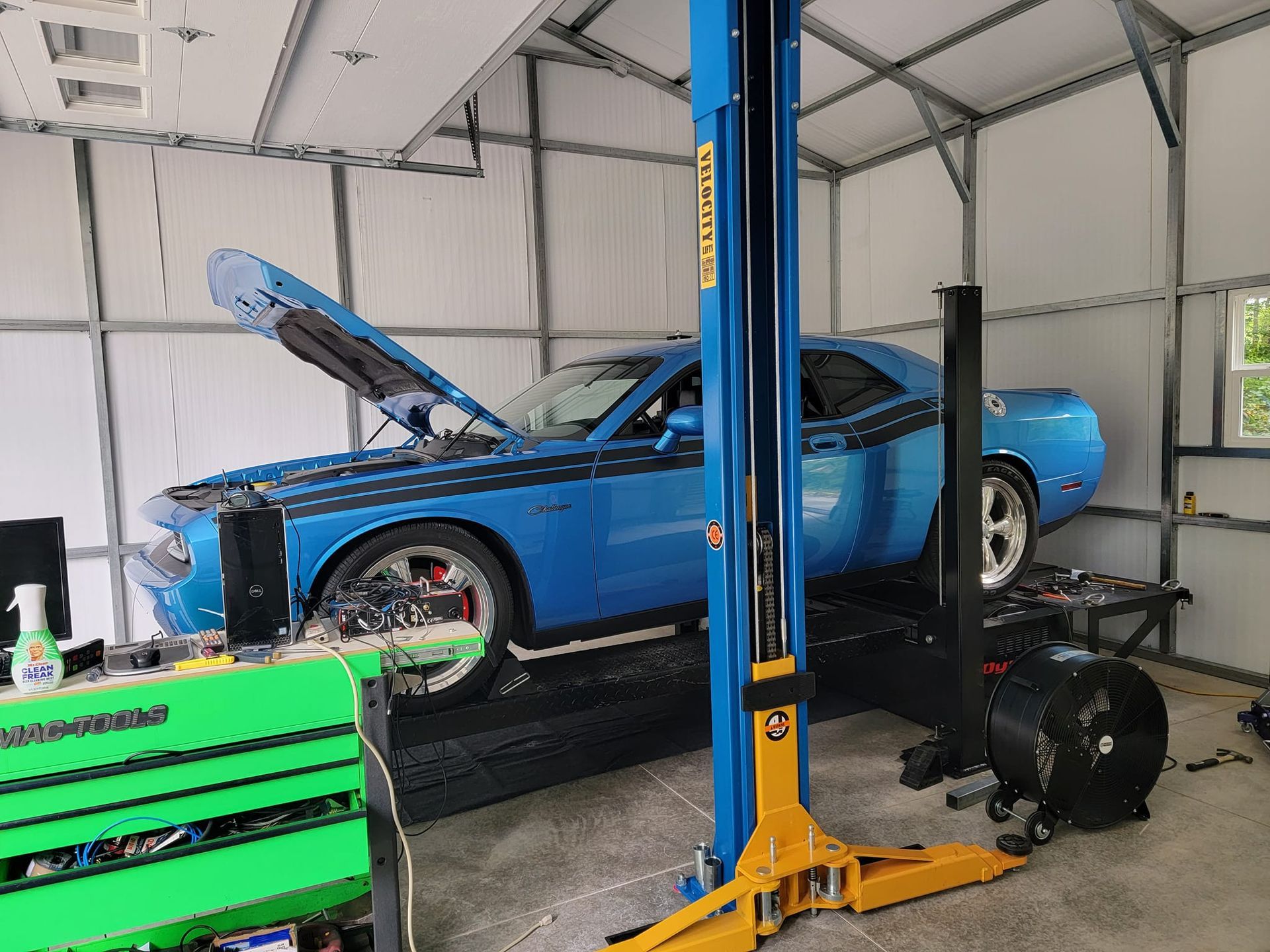 A blue dodge challenger is on a lift in a garage.
