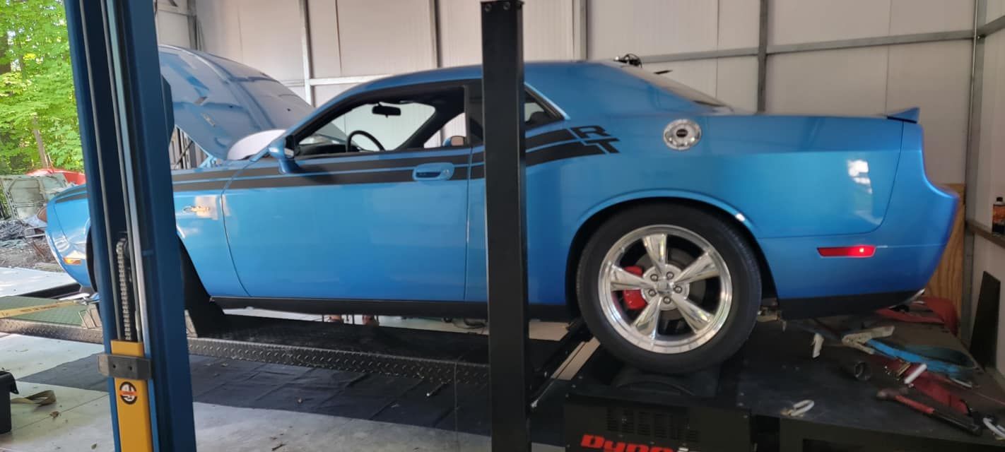 A blue dodge challenger is on a lift in a garage.