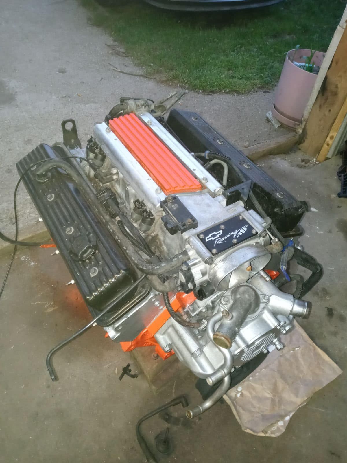 A car engine is sitting on the ground in a garage.