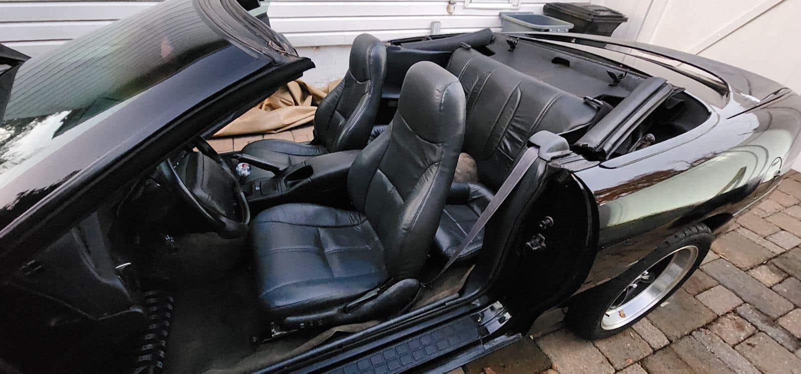 The inside of a black convertible car with the top down.